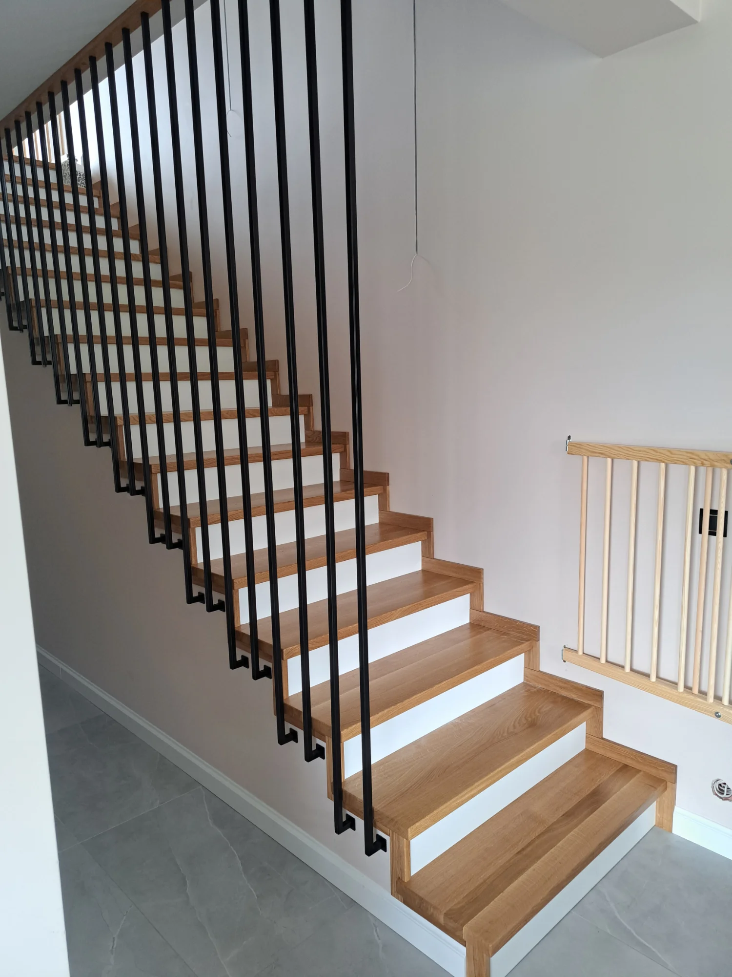 Schody zabiegowe typu L, połączenie stopni dębowych z minimalistyczną barierką metalową