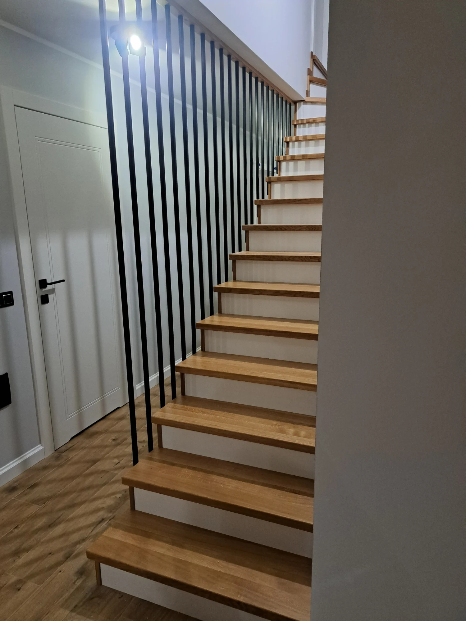 Schody dębowe z białymi podstopnicami, zbliżenie na strukturę drewna dębowego i wykończenie lakierem