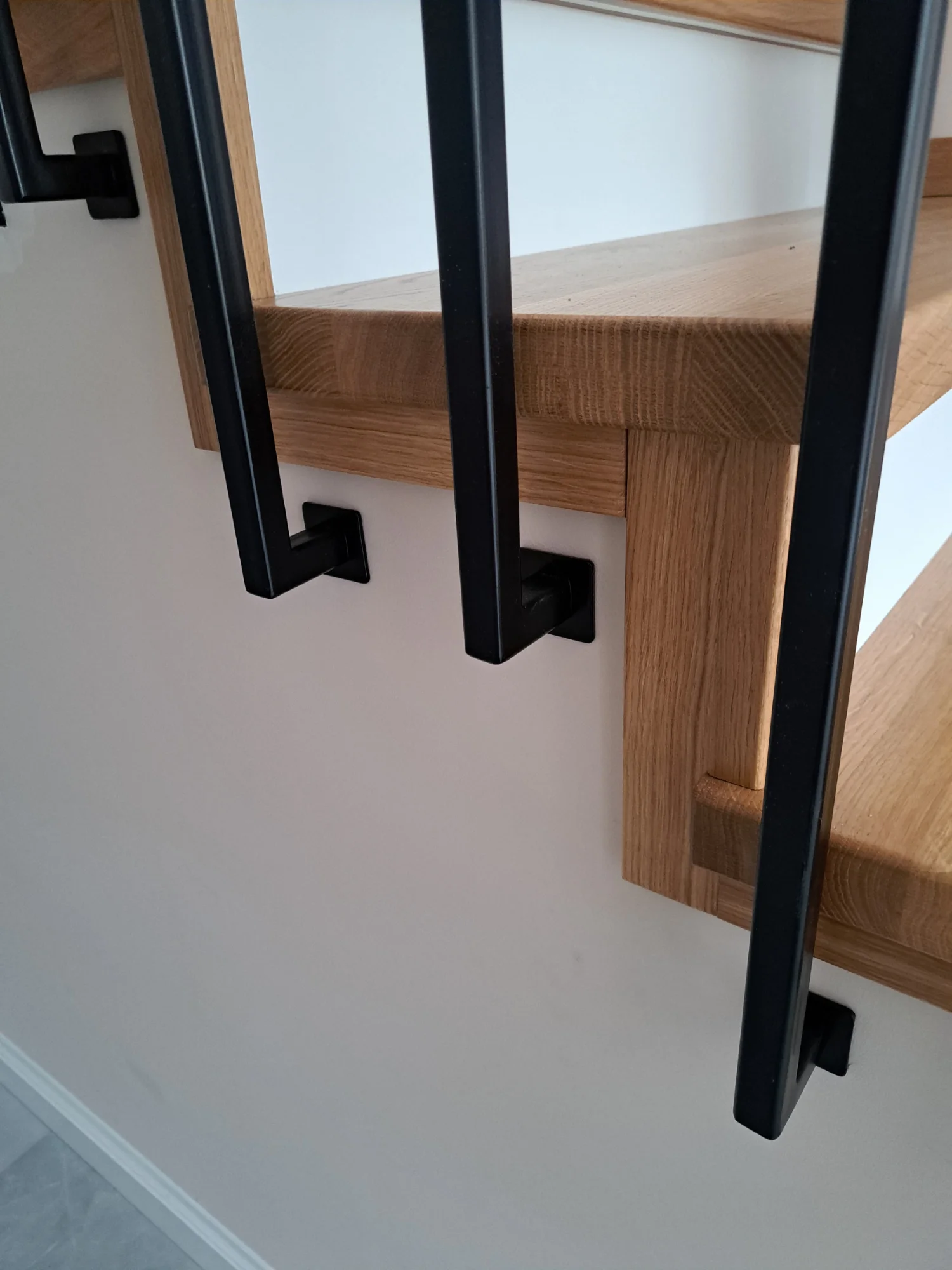 Zbliżenie na Schody dębowe zabiegowe na beton Gdańsk, listwy maskujące i białe podstopnice, stolarz Gdańsk