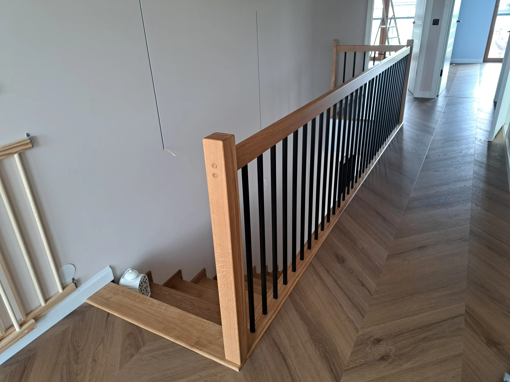 Wykończenie schodów przy ścianie, listwy maskujące i białe podstopnice, stolarz Gdańsk