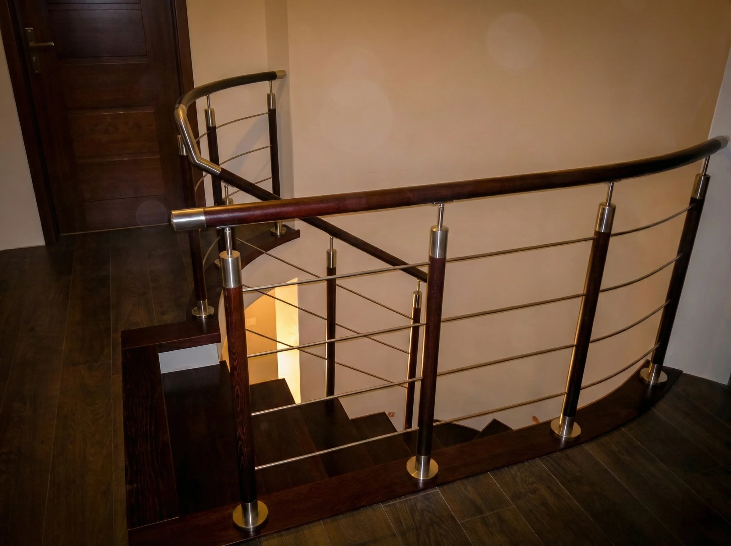 Widok schodów wewnątrz domu, kontrast ciemnego drewna i jasnych ścian