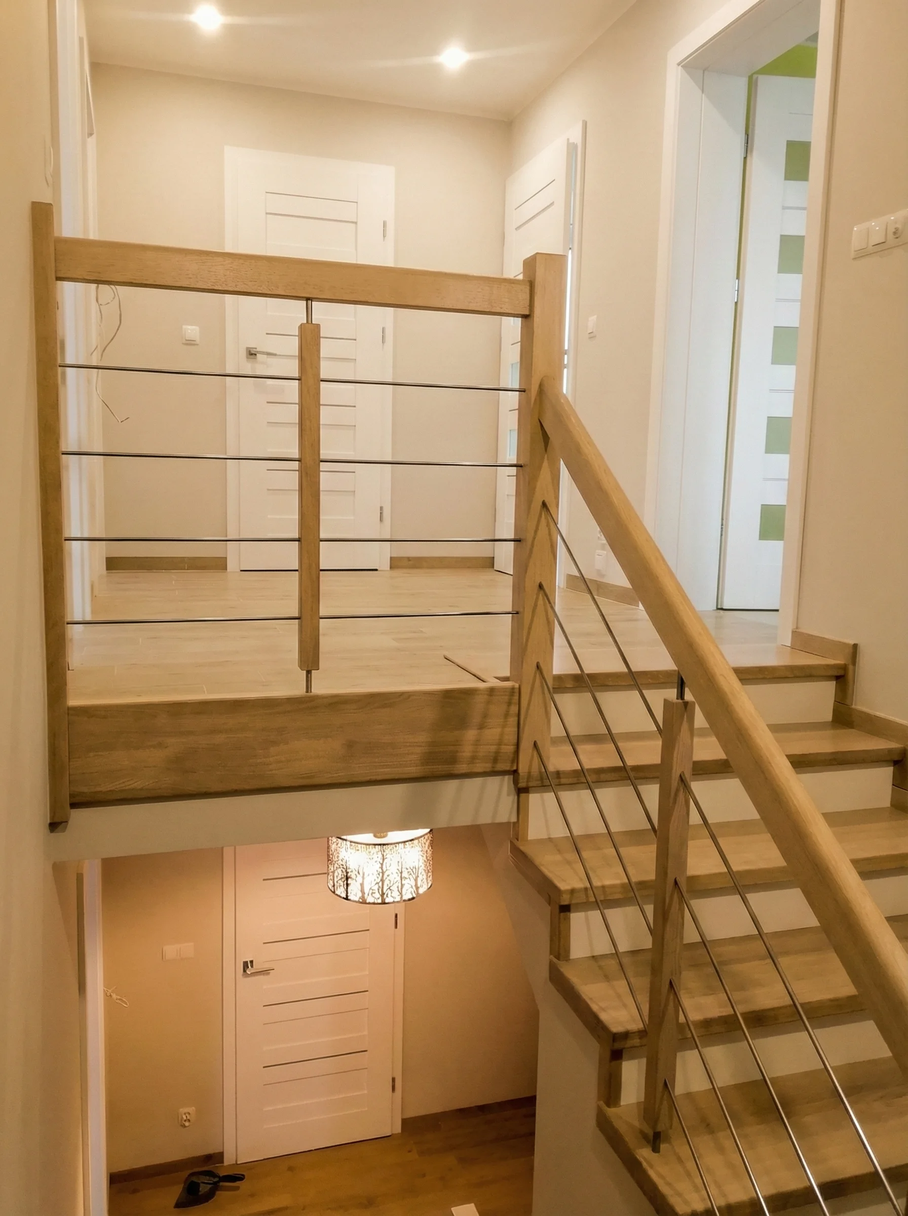 Widok schodów z podestem, połączenie drewna i bieli