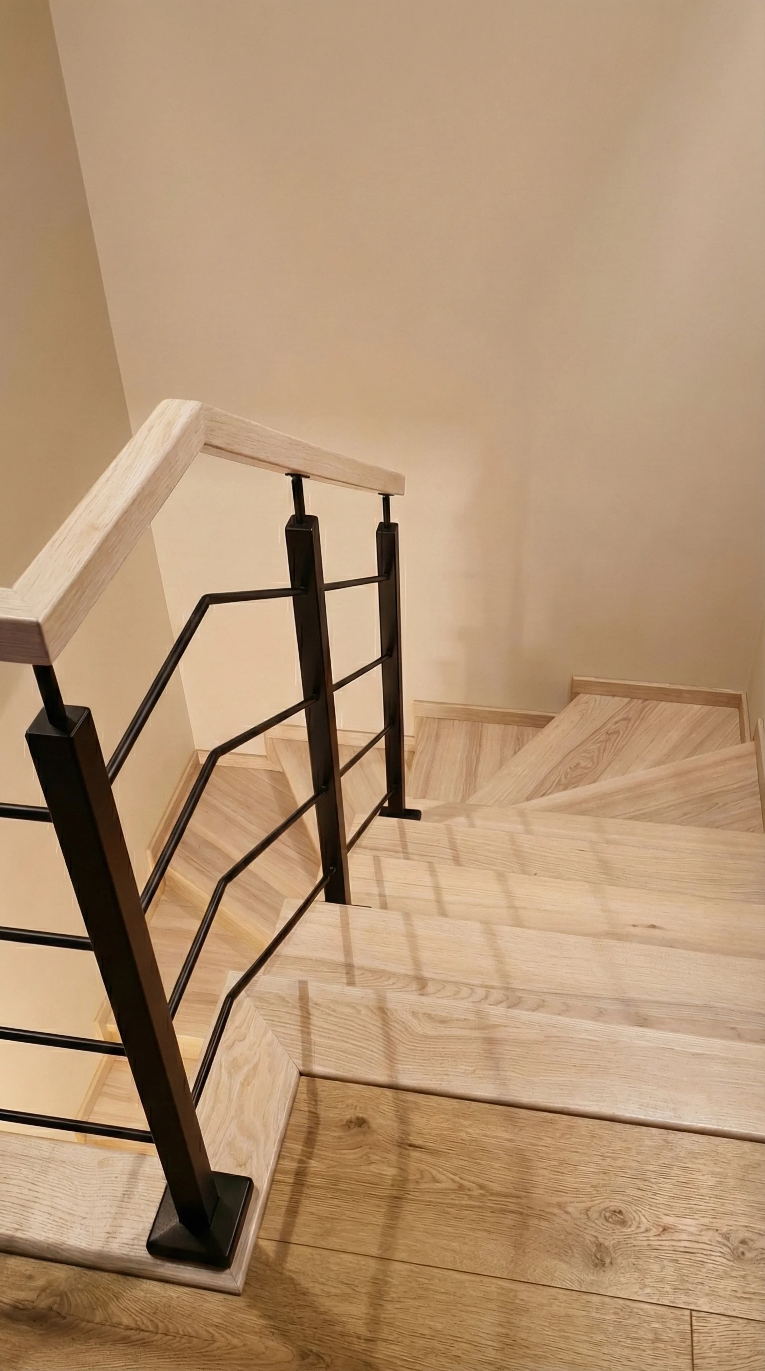 Widok klatki schodowej z góry, kontrast drewna i bieli